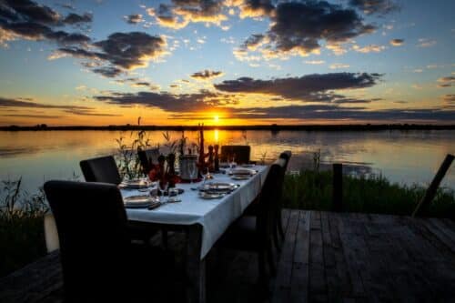A dinner set on the riverbanks of Botswana with sunset views