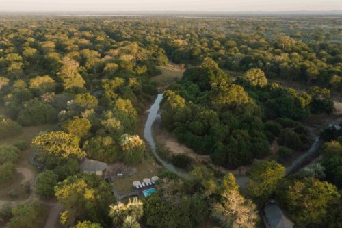 Aerial scene of winding dirt roads through golden woodland near Muzimu Tented Camp, Gorongosa