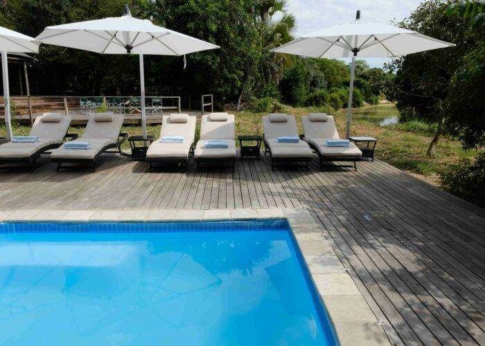 Swimming pool surrounded by sunbeds at Muzimu Tented Camp in Gorongosa, Mozambique