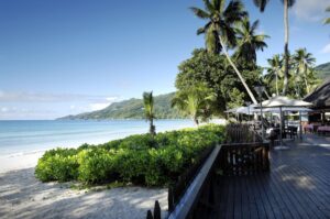 Beachfront terrace dining at Berjaya Beau Vallon Bay Resort overlooking white sands and clear Indian Ocean