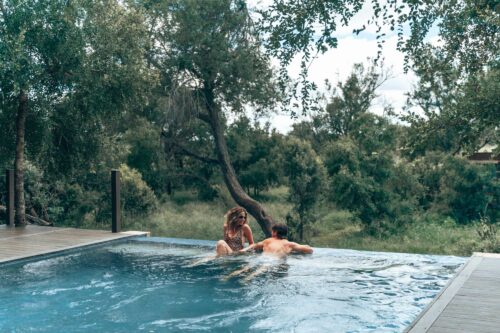 Couple relaxing in the infinity pool overlooking the bush at Honeyguide Mantobeni Camp